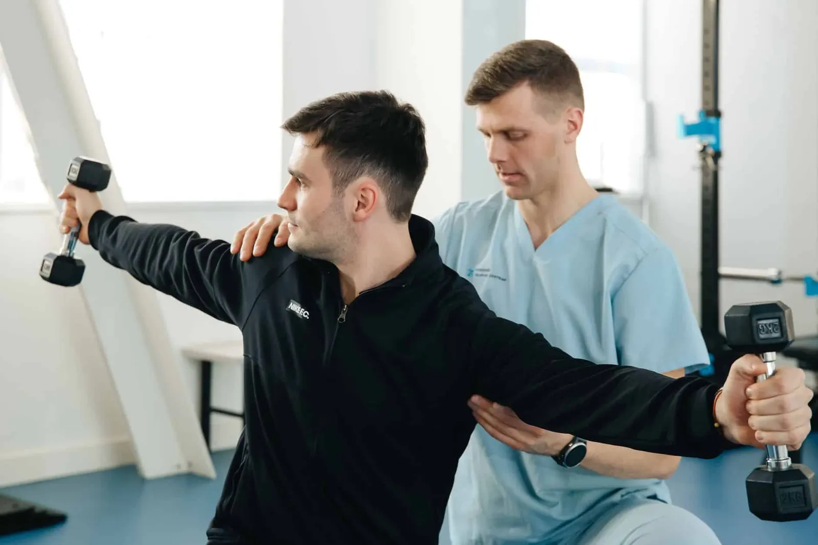 Kinésithérapeute accompagnant un patient pendant un exercice de renforcement au cabinet