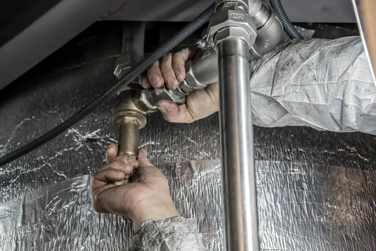 Mains d'un plombier installant des tuyaux en acier lors d'un chantier
