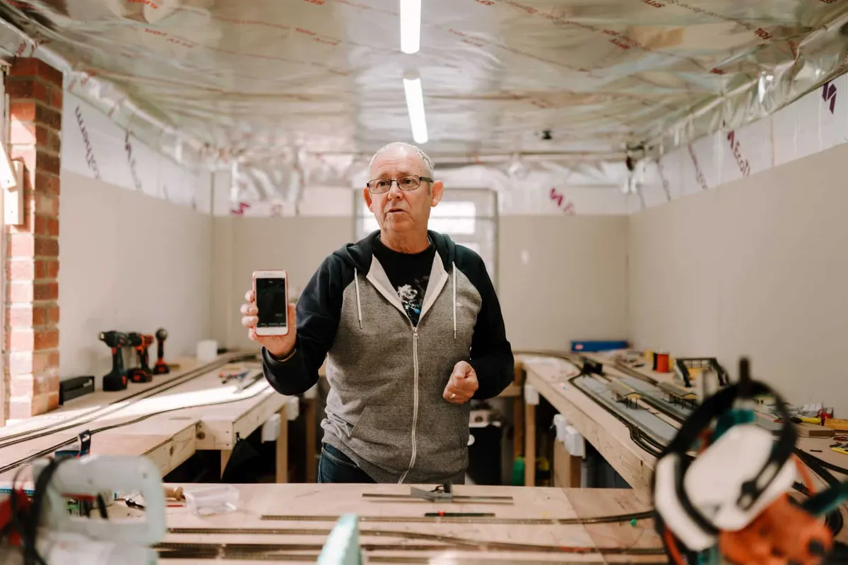 Artisan dans son atelier consultant son smartphone